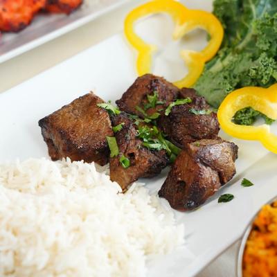 Beef kebab served with kale salad, bell pepper slices and rice.