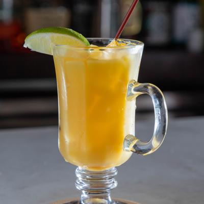 Screwdriver cocktail served in a stemmed glass mug with a handle and a lime garnish.