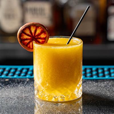 Whiskey Sour served in a rocks glass with a straw and a dry citrus wheel.