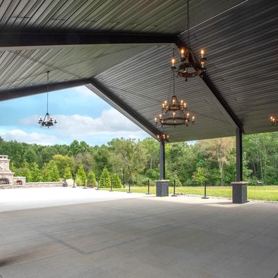 Outdoor area for large gatherings, covered with a roof with hanging chandeliers.