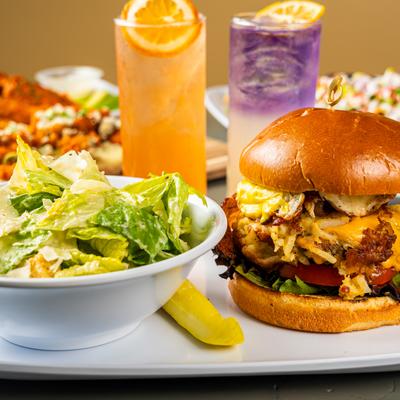 Fried chicken sandwich served with a side Caesar salad and drinks.