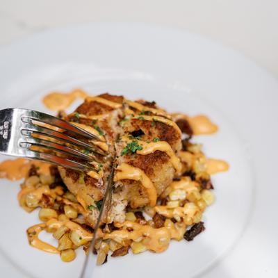Crab cake with corn and spicy aioli on a plate