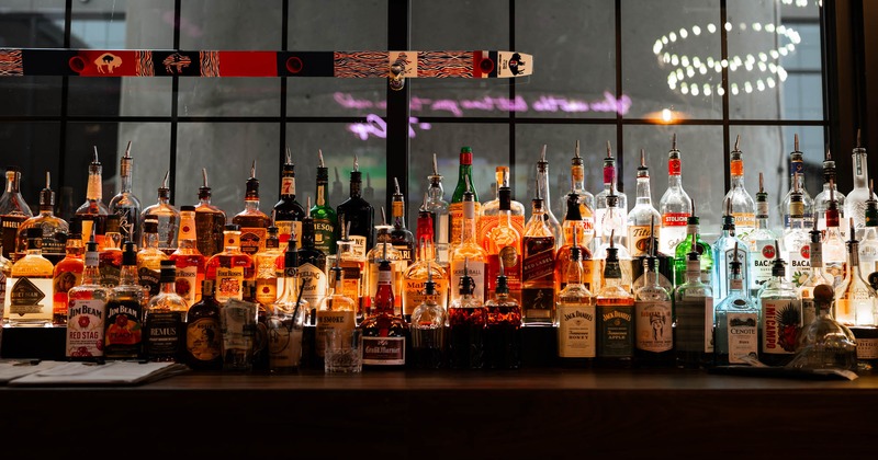 Assorted liquor bottles lined up on a bar top