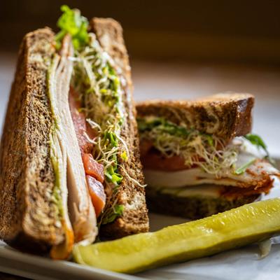 Sandwich with salsalito turkey, mayo, tomato, arugula, sprouts, and avocado.