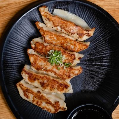 Pan-seared gyoza served on a black plate, overhead view.