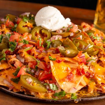 Nachos topped with melted cheese, jalapenos, tomatoes, onions, and cilantro.