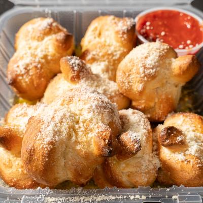 Garlic knots served with marinara sauce on the side.