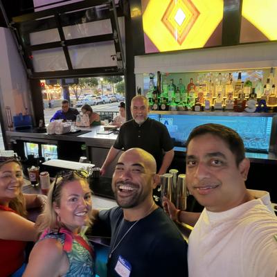 two men and two womem smiling at the bar, with the bartender in the background smiling.