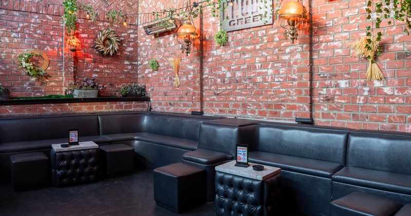 Interior, lounge area, banquette bench with coffee tables and tabourettes, red brick walls