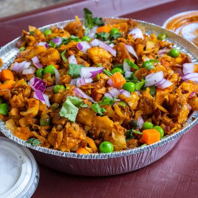 Chicken biryani served in a foil container, accompanied with chutneys.