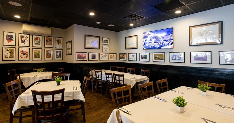 Interior, white cloth tables, tables for four and six people, various framed pictures