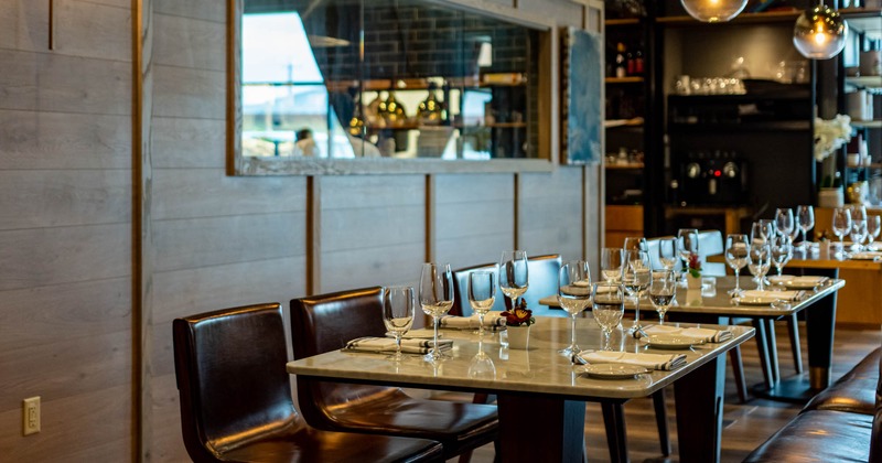 Interior, lined up dining tables with tableware and leather chairs