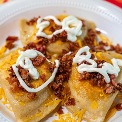 Loaded Potato Pierogi, topped with sour cream, shredded cheddar, and bacon bits.