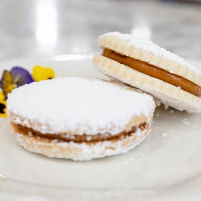 Alfajores sandwich cookies dusted generously with powdered sugar.