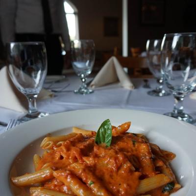 Penne pasta in creamy tomato sauce on a white plate.