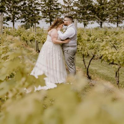 Wedding couple standing between the vines at Next Chapter Winery.
