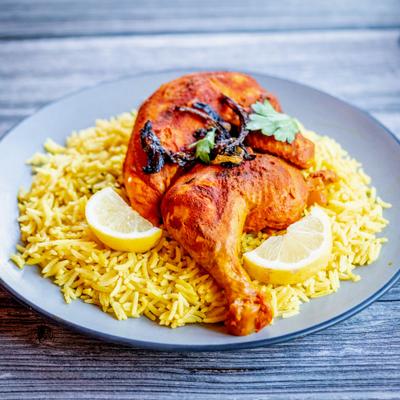 Chicken served over rice and garnished with lemon slices.