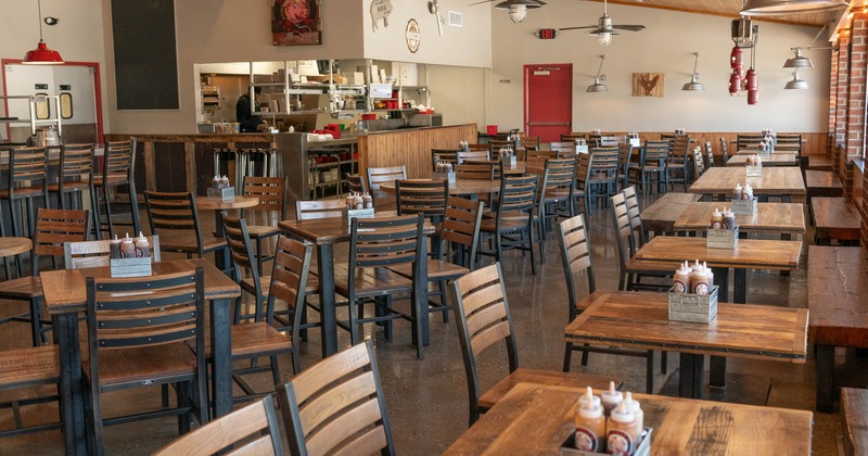 Interior, seating area, tables and chairs ready for guests, kitchen in the back
