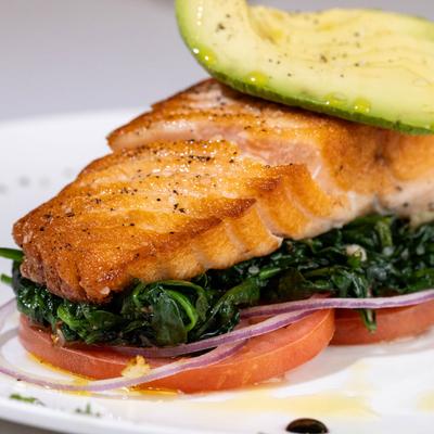 Grilled Salmon topped with avocado slices, served over spinach, tomatoes, and red onion.
