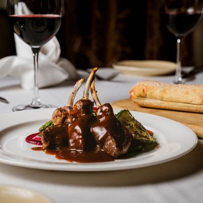 Lamb chops covered in brown sauce, served with bread and red wine.