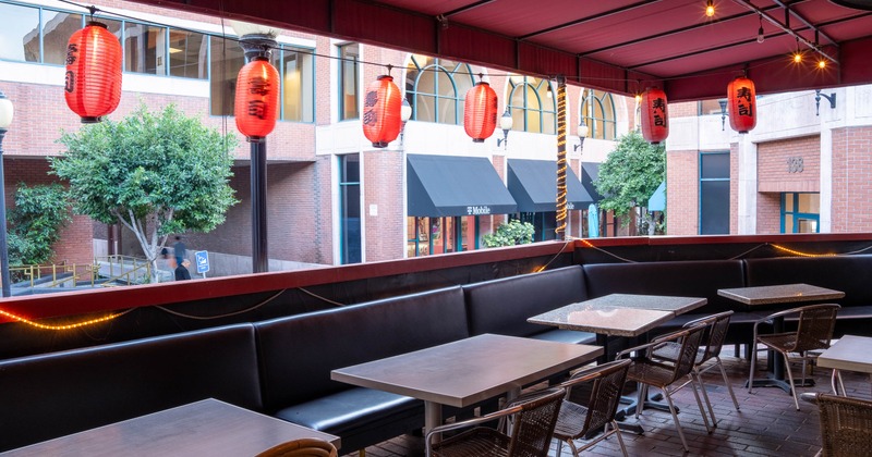 Outdoor seating area with red lanterns and metal tables under a red canopy