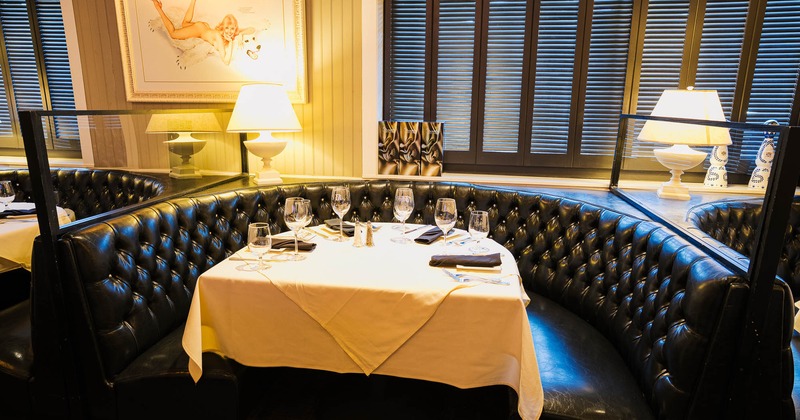 Restaurant booth with tufted black leather seating and a round table set for dining