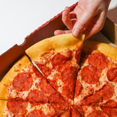A hand taking a slice of pepperoni pizza, top view