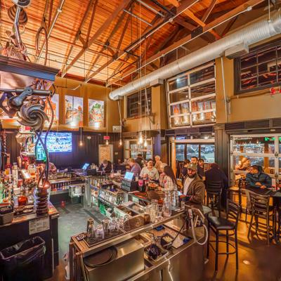 People enjoying food and drinks at a bar with high seating and industrial design.