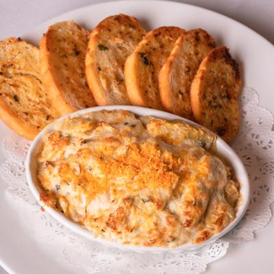 Crab and artichoke fondue served with toasted bread slices.