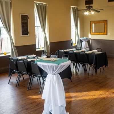 A room with tables set up for dining, with chafing dishes on a table.