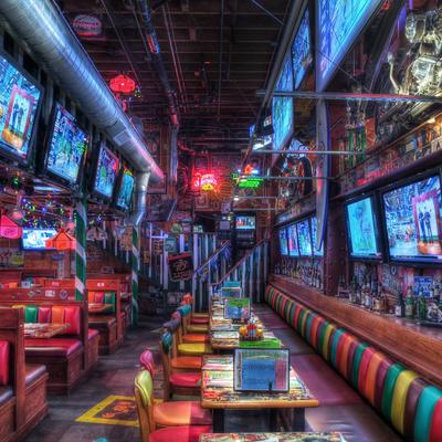 Vibrant sports bar with multicolored booths, numerous TVs, neon signs and eclectic decor