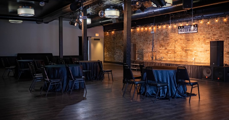 Event venue with brick wall, stage, and round tables