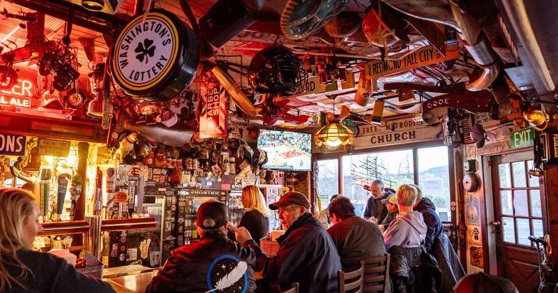 Patrons enjoying drinks at the bar featuring lots of decorative items on the ceiling