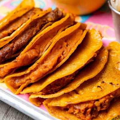 Crispy folded tacos on metal tray.