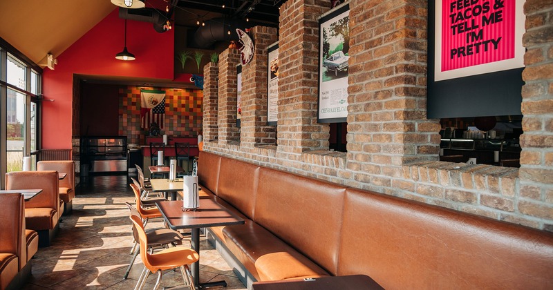 Interior, banquette seating by a wall, booths by the window side