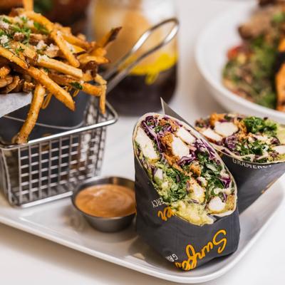 Grilled chicken wrap with cabbage, greens, fries, and dipping sauce.