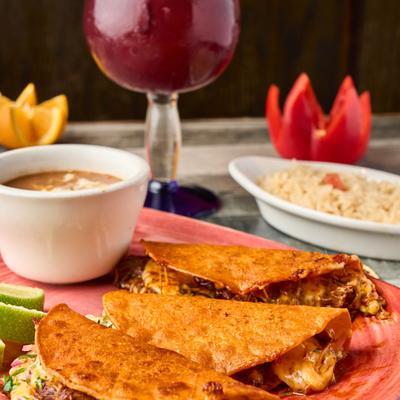 Birria tacos served with lime wedges, served with rice and consommé.