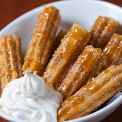Extreme close up of churros with whipped cream and caramel drizzle on top
