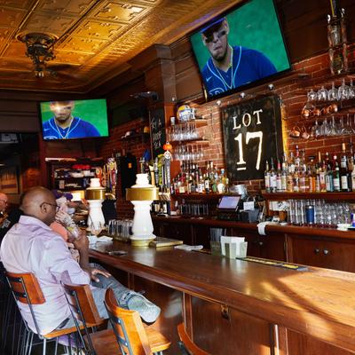 Customers sitting at the bar and watching a game.