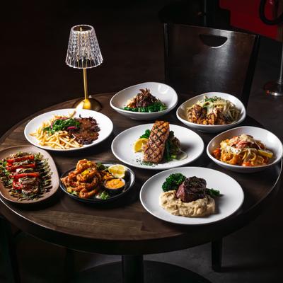 Table filled with assorted plated dishes under a lamp.