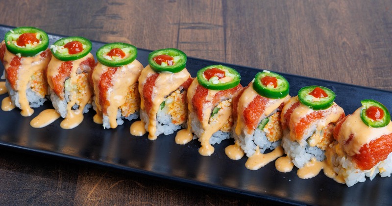 Sushi rolls topped with salmon and jalapenos
