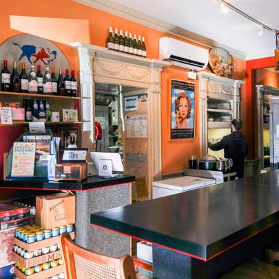Interior, restaurant counter with crates of beverages and wine bottles on the rack