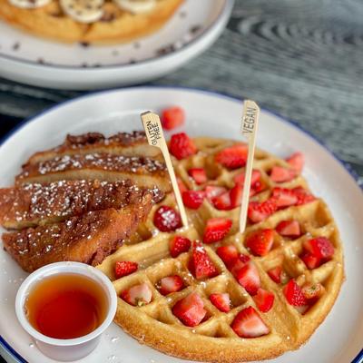 Belgian waffle with powdered sugar and strawberries, served with chicken and syrup