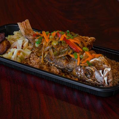 Whole fried fish with sauteed vegetables, fried plantains, and cabbage.