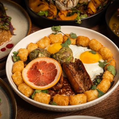 Mexican skillet with tater tots, fried egg, sausage and guacamole.