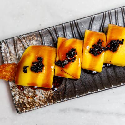 Ichiban Roll topped with thin slices of mango and garnished with black tobiko.