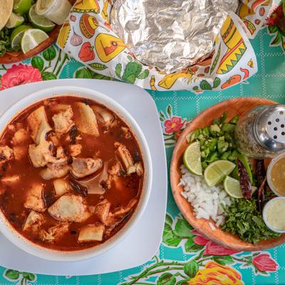 Bowl of Menudo soup served with classic garnishes and a tortilla.
