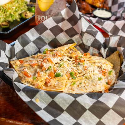 A basket of cheesy quesadillas topped with pico de gallo and parmesan.
