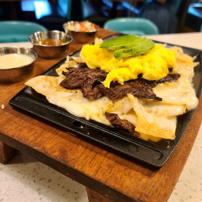 Chilaquiles blanco served on an iron skillet and topped with scrambled eggs and avocado..