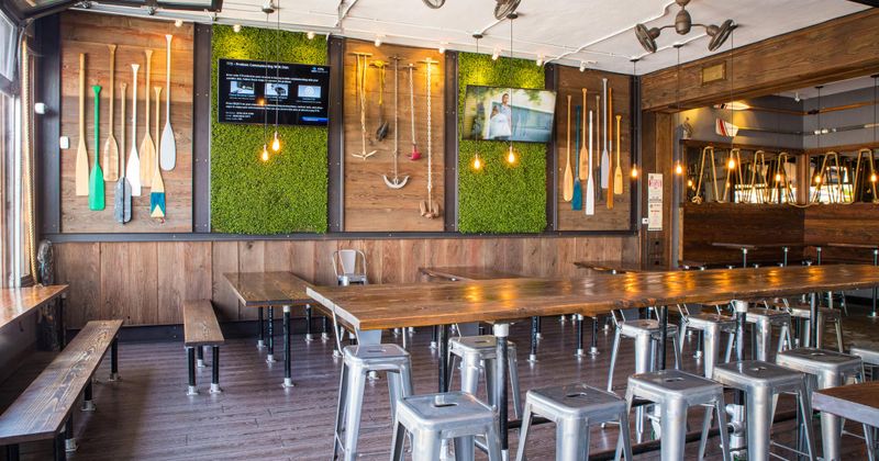 Interior, long table with bar stools, lined up short tables with benches, wall decorations